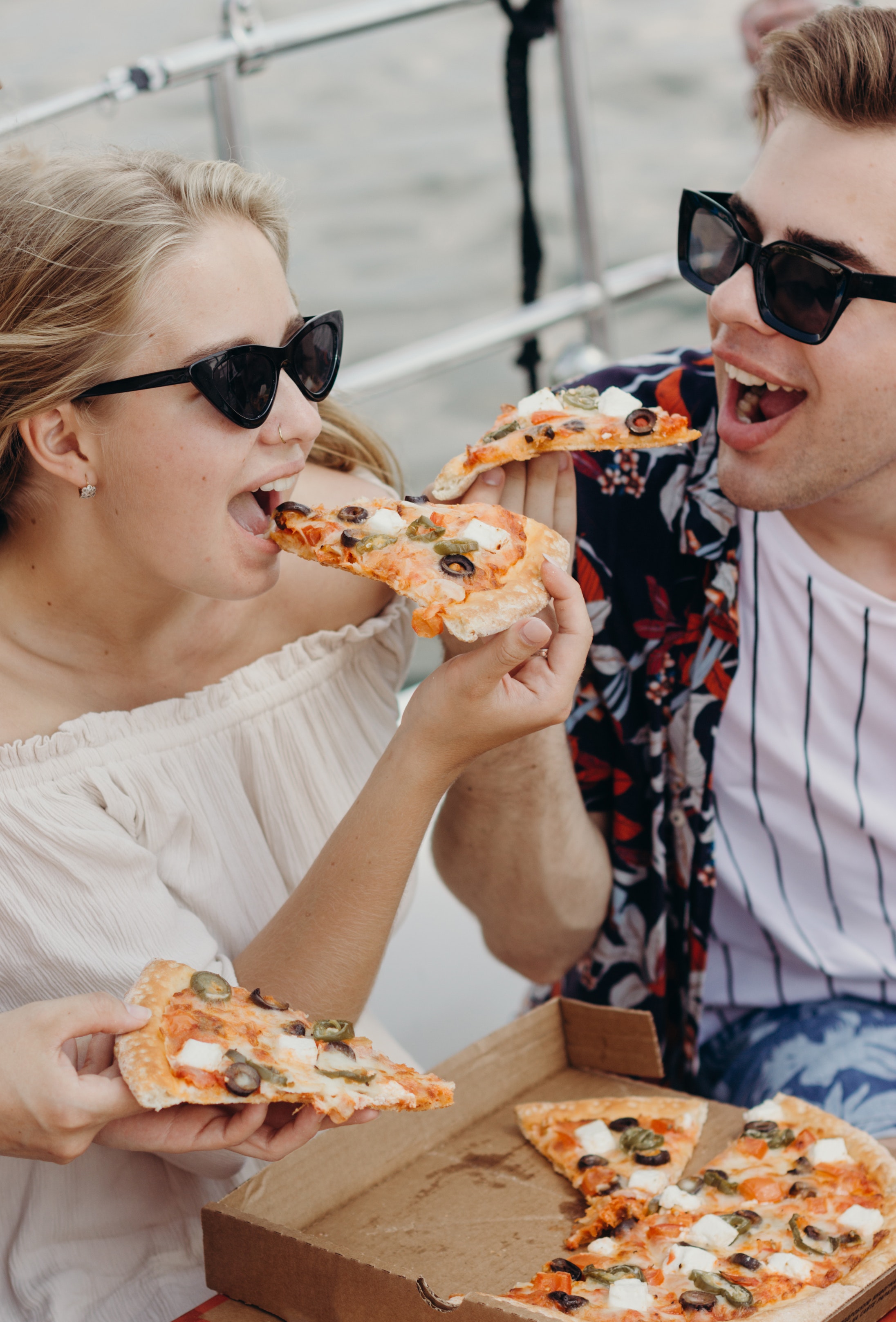 Couple eating pizza in the sun looking happy